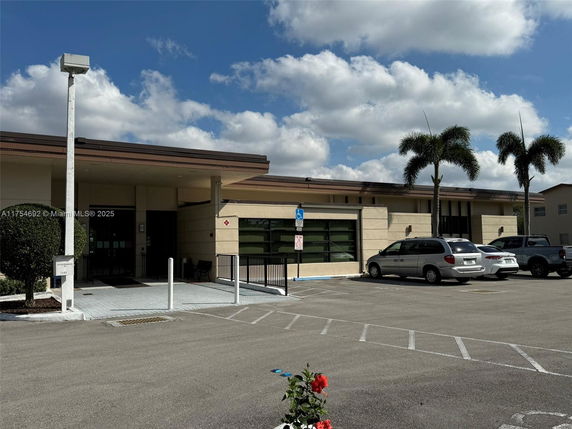 Front view of a single-story building with an entrance and parking area.