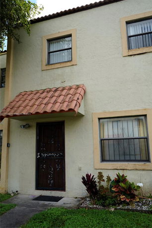 Front view of a two-story house with a metal door and tile awning.