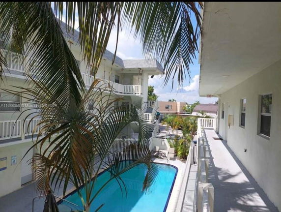 View of a swimming pool area with adjacent multi-story buildings.