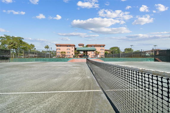 Tennis court in front of a multi-story building.
