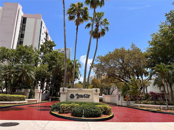 View of building entrance with palm trees and a sign at Plaza of the Americas.