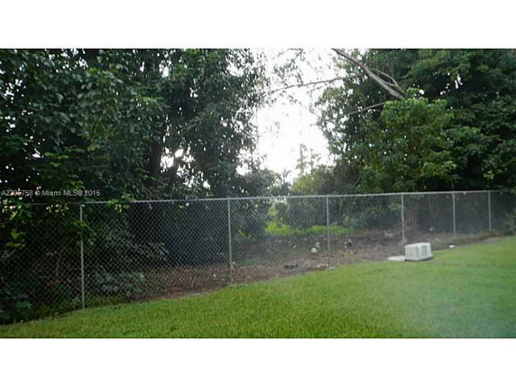 Outdoor area with a chain-link fence and surrounding trees.