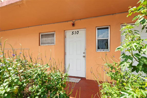 Front view of a building entrance with an orange facade and white door.