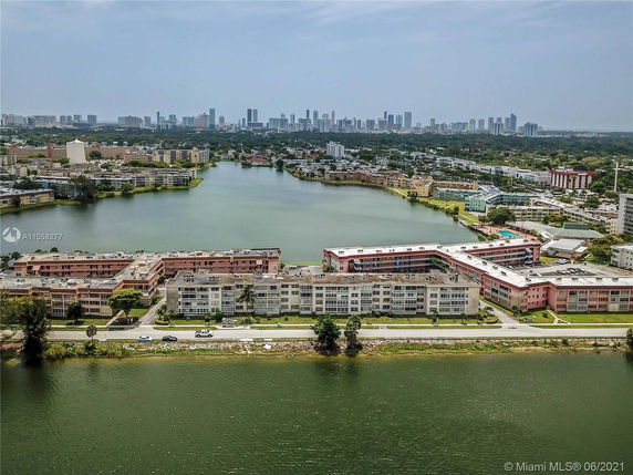 Aerial panoramic view of a waterside cityscape with residential buildings in the foreground and a skyline in the background.