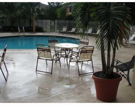Outdoor swimming pool area with chairs and a table nearby.