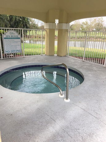 Outdoor view of a round spa pool with safety railings under a covered area.
