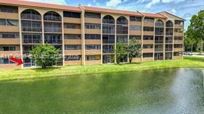 Front view of a multi-story apartment building overlooking a pond.