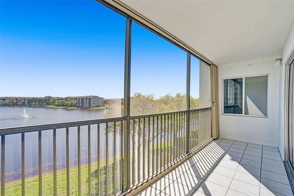 Balcony with railing overlooking a lake and a distant building.