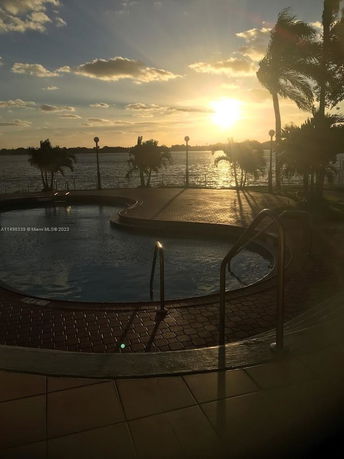 Outdoor swimming pool with a scenic sunset view over a body of water.