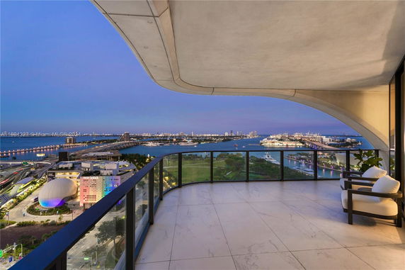 Panoramic view of a cityscape with waterway from a curved balcony at dusk.