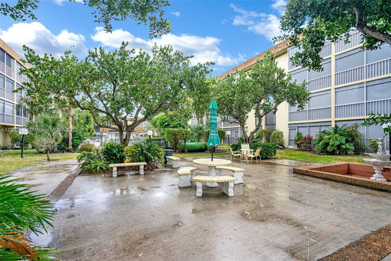Courtyard with seating and trees surrounded by multi-story apartment buildings.