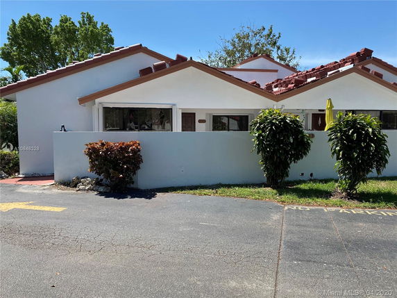 Front view of a single-story house with a white exterior and red-tiled roof.