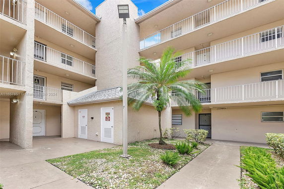 Outdoor view of a multi-story building with balconies and a central courtyard area.