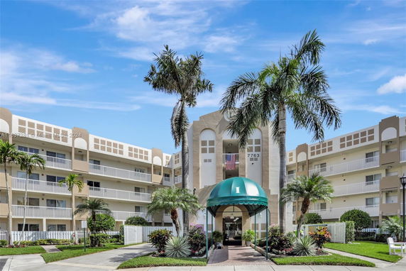 Front view of a multi-story apartment building with balconies and a green awning.