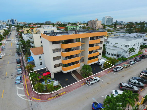 Front view of a multi-story apartment building with orange accents and balconies.