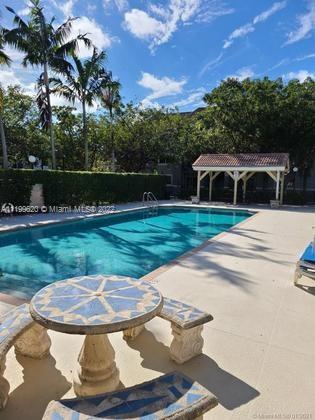 Outdoor swimming pool with a decorative table and palm trees in the background.