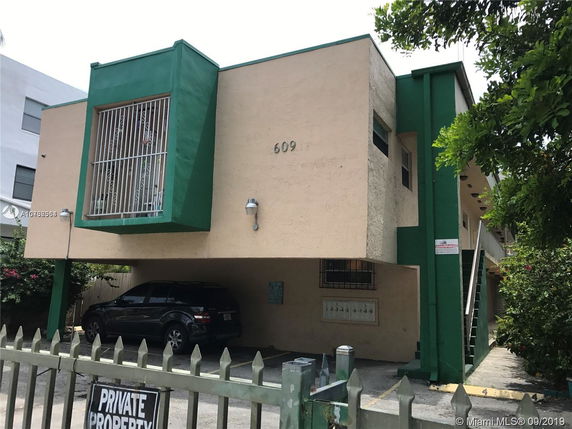 Front view of a two-story building with green accents and gated parking.