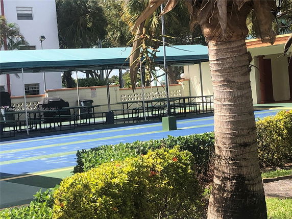 Outdoor area with benches and a covered sports court.