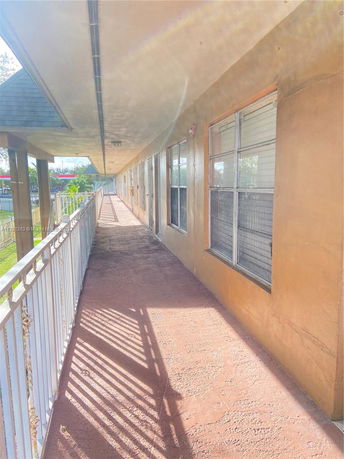 Corridor view of a building with railing and windows.
