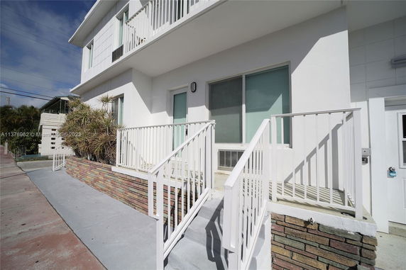 Front view of a two-story building with white railings and a small entrance.