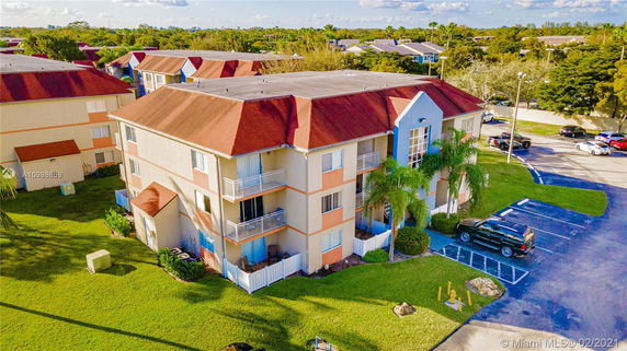 Front view of a multi-story apartment building with balconies and red roofs.