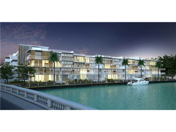 Front view of a modern waterfront residential complex with multiple stories and palm trees.