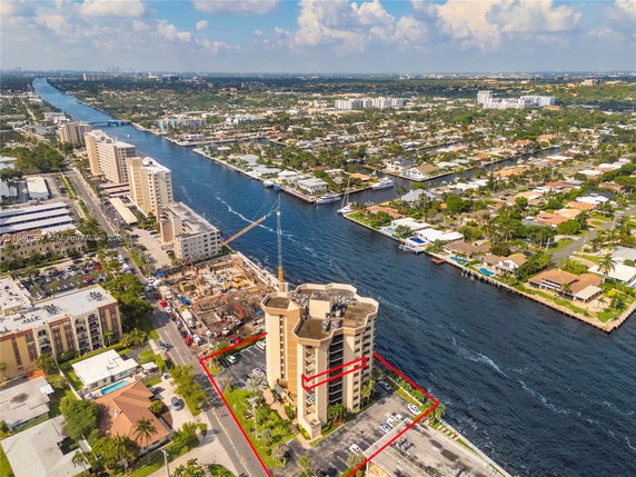 Aerial view showcasing a high-rise building situated by a river, surrounded by a mix of residential and commercial structures.