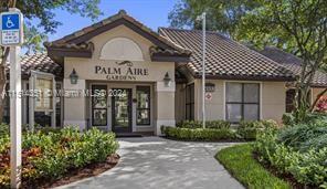 Front view of a building with a tile roof and entrance sign reading 'Palm Aire'.