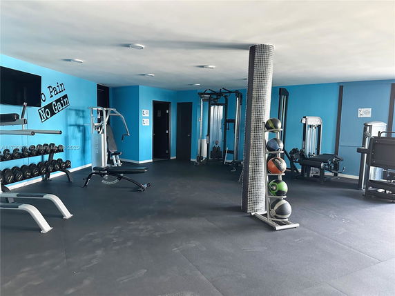 Indoor gym area with exercise equipment and weights.