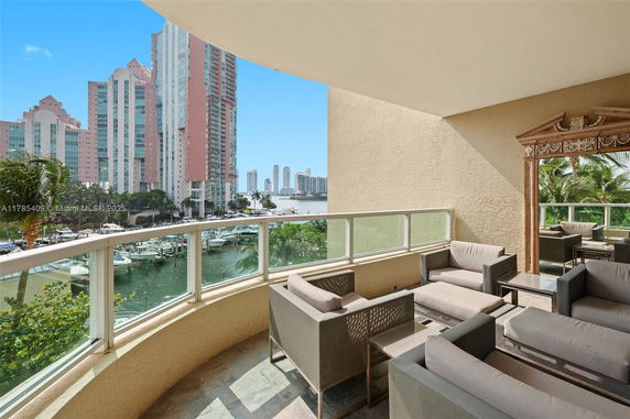 Terrace area with outdoor seating overlooking a marina and high-rise buildings in the background.
