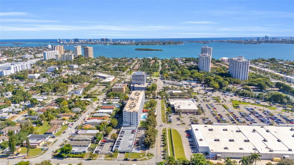 Aerial view of a cityscape with numerous buildings and a water body in the background.