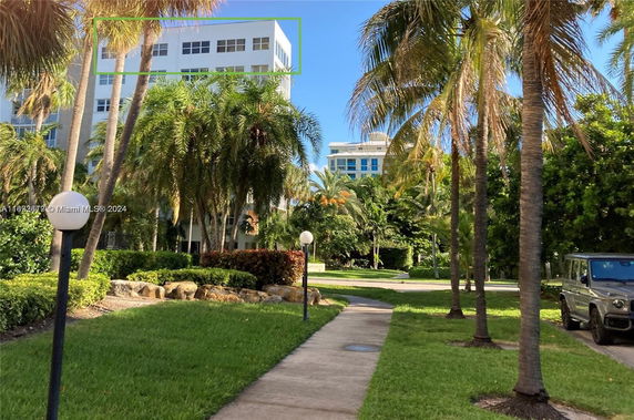 View of buildings surrounded by palm trees and greenery.