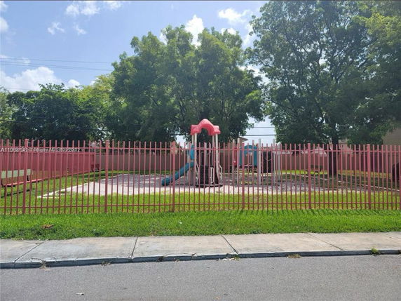 Playground with red fencing, trees in the background.