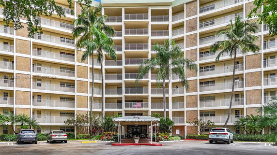 Front view of a multi-story residential building with balconies and parking area.