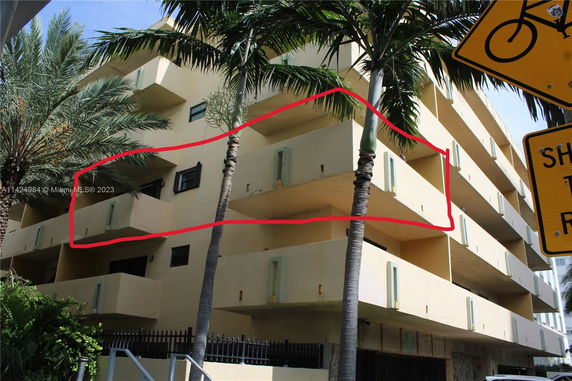 Front view of a multi-story building with balconies and palm trees.
