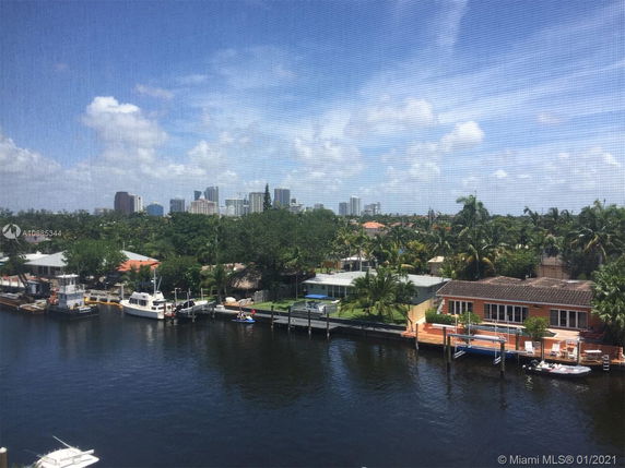 View of waterfront houses and boats with city skyline in the distance.