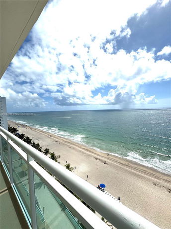 Panoramic view from a building balcony overlooking the beach and ocean.