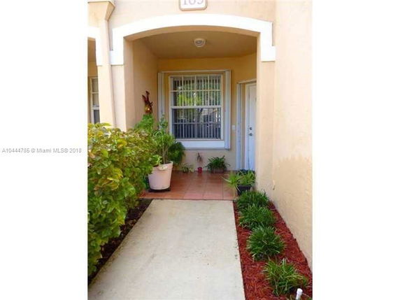 Front entrance of a house with a covered porch and decorative plants.