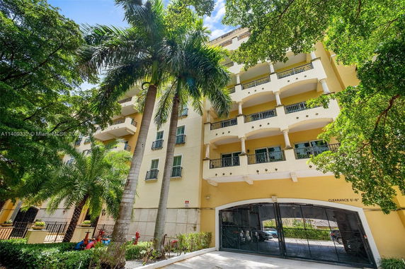 Front view of a multi-story building with balconies and an arched entrance.