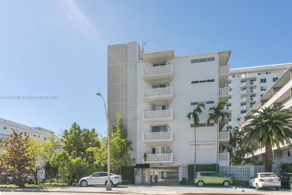 Front view of a multi-story residential building with balconies and a gated entrance.