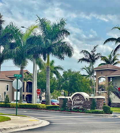 Front view of a residential complex with a main sign and palm trees.