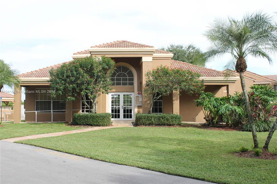 Front view of a single-story house with arched windows and a terracotta roof.
