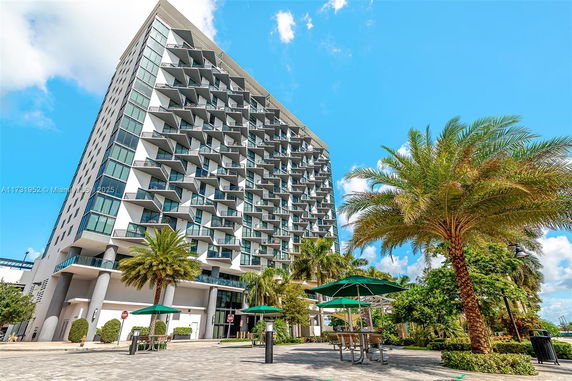Front view of a modern multi-story building with balconies and large windows.