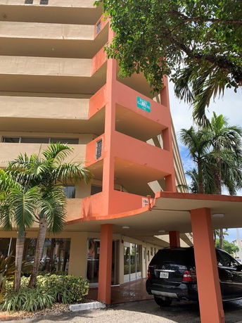 Front view of a multi-story building with a covered entrance and adjacent parking area.