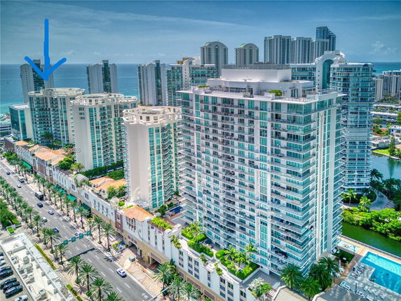 Aerial view of a cluster of high-rise residential buildings with glass balconies near the ocean.
