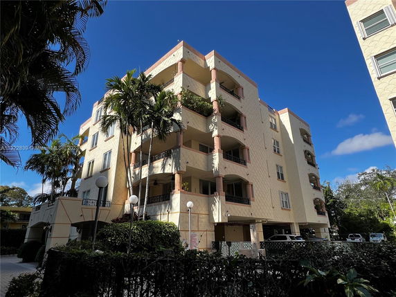 Front view of a multi-story residential building with balconies and light colored exterior.
