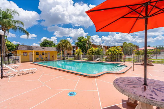 Outdoor swimming pool area with lounge chairs and a small building nearby.