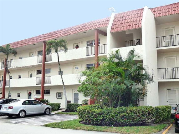 Front view of a three-story apartment building with balconies and red tile roofing.