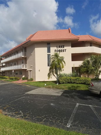 Front view of a multi-story building with balconies and a sloped roof.
