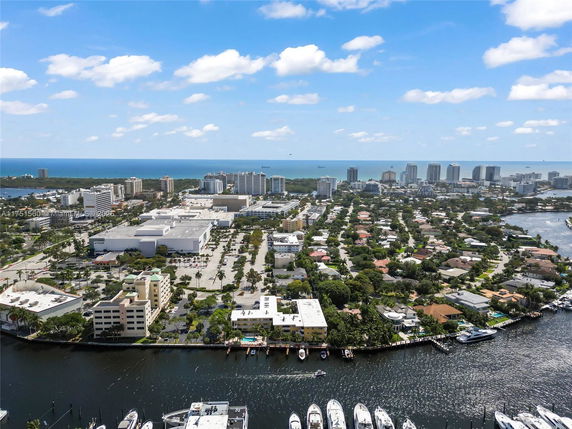 Aerial panoramic view of a coastal cityscape with residential and commercial buildings, waterways, and the ocean in the background.